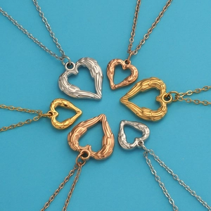 Detailed view of heart wing pendants in silver gold and rose gold on a blue surface