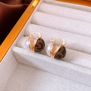 Detail of leopard print velvet and pearl stud earrings on a cream jewelry tray