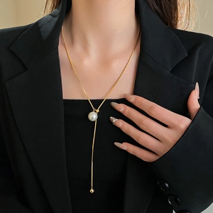 Detail of gold Y-shaped snake chain necklace with pearl pendant worn by a model