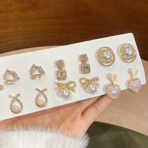 Close-up of seven pairs gold earrings set with pearls, zircons and pink cat eye stones