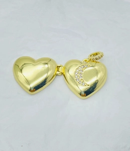 Close-up of a gold heart locket with a diamond crescent moon on white paper