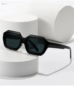 Vue détaillée de lunettes de soleil rectangulaires noires sur un socle blanc moderne