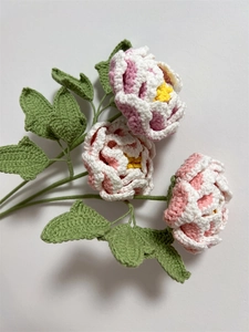 Detailed view of handmade knitted pink and white peony crochet bouquet with green leaves