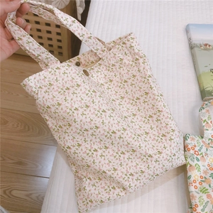 Détail d'un petit sac en tissu floral avec fermeture à bouton en métal bronze