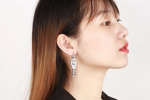 Side view of punk style silver skull drop earrings with chunky chains on model