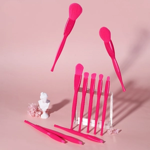 Artistic detail of pink makeup brush set with various tools and creative props
