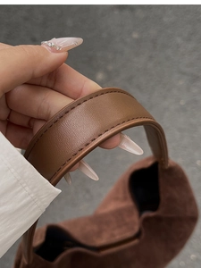 Close-up of brown suede bucket bag featuring litchi grain leather strap and neat stitching