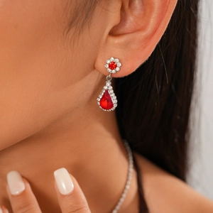 Close-up of a model wearing silver water drop earrings with red stones and crystals