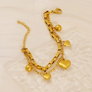 Élégant bracelet double chaîne dorée avec pendentifs cœur sur une surface en verre texturé
