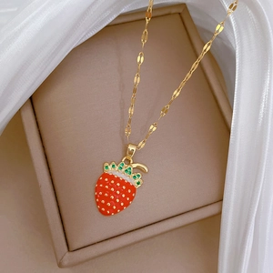 Close-up of strawberry pendant with red enamel, green crystals and gold chain