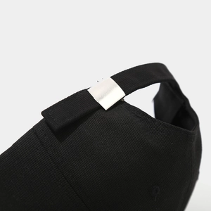 Close-up of black cotton baseball cap showing adjustable silver metal buckle and strap