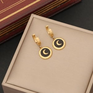 Golden moon earrings with black circular pendants set in a stylish jewelry box