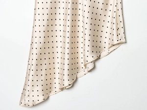 Détail de robe satinée à pois avec ourlet asymétrique et texture de tissu fluide