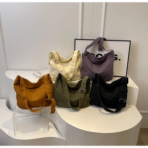 Detail showing various colors of canvas crescent tote bags with adjustable straps