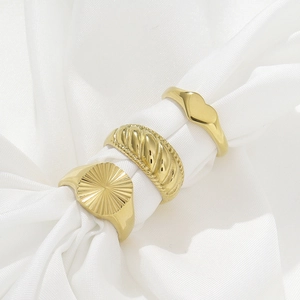 Three-piece gold stainless steel ring set with heart and twist designs on white silk