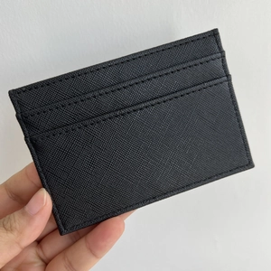 Close-up of black Saffiano leather card holder with two slots and precise edge stitching
