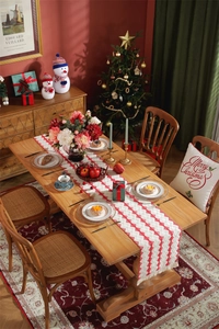 Close-up of a festive red and white cotton table runner with tassels and Christmas decor