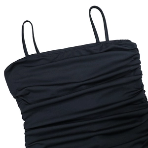 Detail of black slim-fit dress featuring ruched texture and delicate spaghetti straps