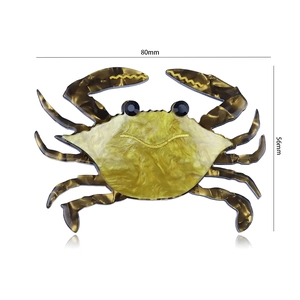 Detail showing an acrylic crab brooch with gold pearlescent shell and tortoiseshell patterns