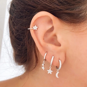 Detail of silver S925 star and moon earrings with crystals on a model's ear