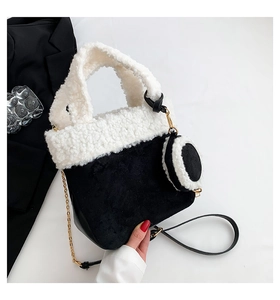 Detailed shot of black faux suede bucket bag with white plush trim and chain strap