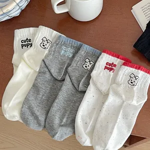 Detail of three cotton socks with cute puppy embroidery and colorful polka dots