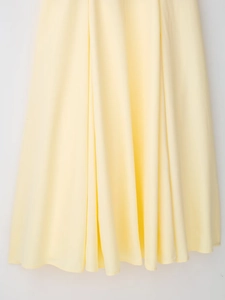 Dettaglio dell'orlo del vestito giallo chiaro con drappeggio premium e trama morbida