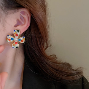 Detailed view of flower ear cuff with colorful crystals and pearls on model's ear