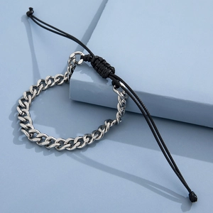 Detail of silver Cuban chain mixed with black adjustable rope braid on a blue block