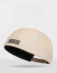 Gros plan sur un bonnet Miki beige avec broderie NEEDS noire au style rétro workwear