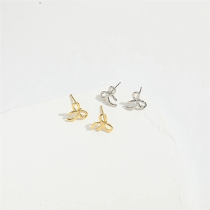 Minimalist bow earrings in gold and silver finish set on white stone display