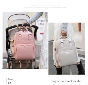 Pink mummy diaper backpack hanging on stroller with grey handle bag outdoors