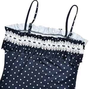 Detail of blue polka dot swimsuit top with white lace trim and ruffle design accents