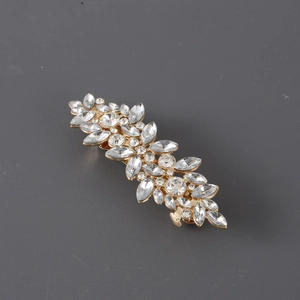 Macro shot of sparkling rhinestones on golden metal hair clip with leaf pattern