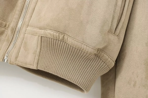 Detailed close-up of premium khaki suede jacket with silver zipper and ribbed hem