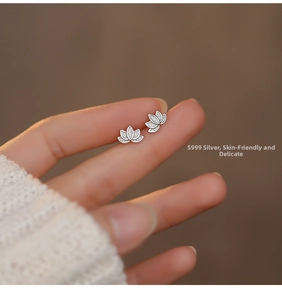 Macro shot of S999 sterling silver lotus stud earrings with pavé micro-diamonds on fingers