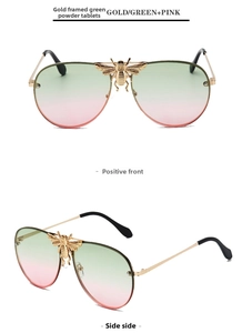 Detailed view of pilot sunglasses featuring golden bee emblem and green pink gradient lenses