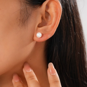 Close-up of elegant round pearl stud earring worn by model with natural lighting