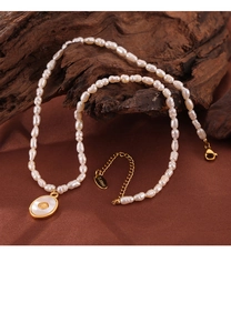 Macro detail of freshwater pearls and white shell pendant on a gold titanium steel chain