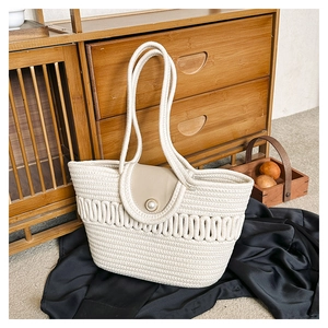 Detail of hand-woven cream tote bag with pearl button closure and thick handles