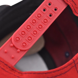 Vue macro détaillée de la fermeture snapback réglable en plastique rouge d'une casquette