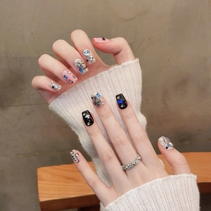 Pink and black press-on nails with 3D silver cross charms and sparkling blue rhinestones