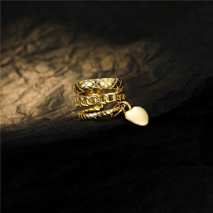 Macro detail of gold-layered rings featuring quilted patterns and a heart pendant