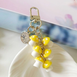 Detail of yellow mushroom keychain with a butterfly engraved silver metal pendant