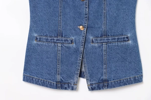 Détail de l'ourlet du gilet en jean bleu avec boutons dorés et surpiqûres orange