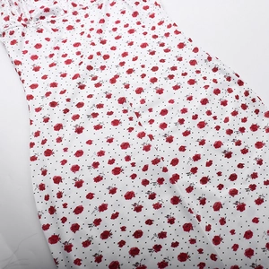 Detalle de primer plano de vestido blanco con flores de rosas rojas y lunares negros