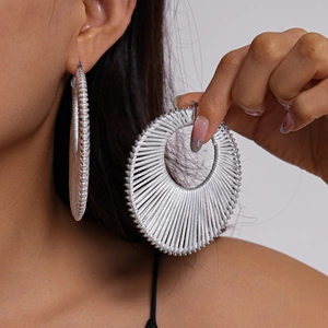 Close-up of oversized silver woven hoop earrings featuring a unique radial textured design
