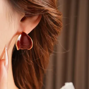 Eleganti orecchini a cuore rosso smaltato a forma di C placcati in oro indossati da modella