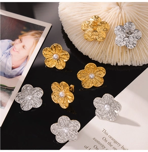 Detailed close-up of textured metal flower earrings with embedded pearls in gold and silver