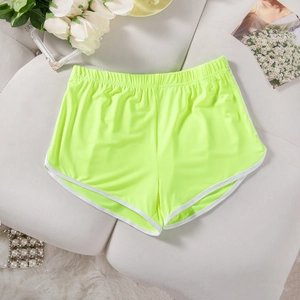 Detail of neon green sports shorts with white trim and elastic waistband on a soft surface